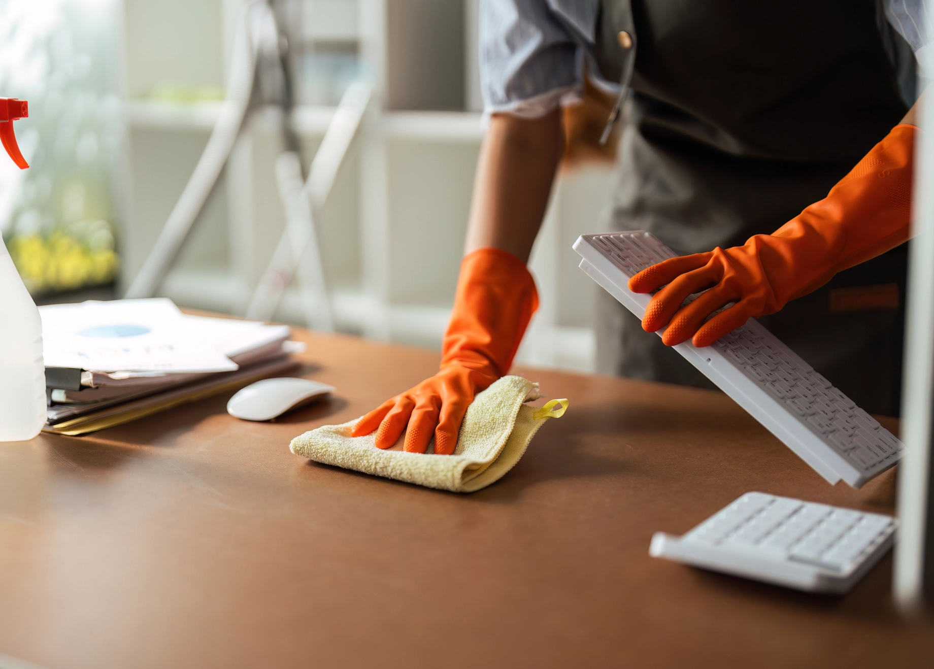 A person in orange gloves cleaning the table.